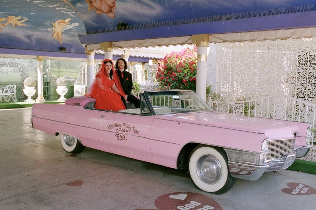 cute couple at a pink cadillac after their ceremony